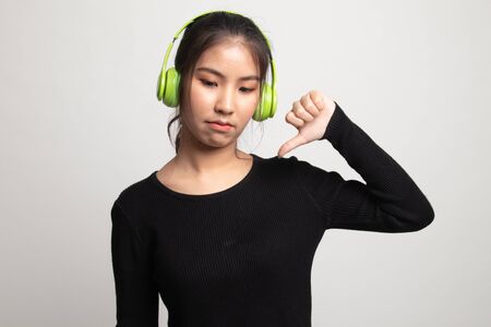 Asian girl don't like  music show thumb down with her headphones on white backgroundの写真素材