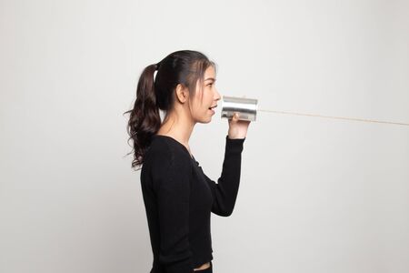 Young Asian woman with tin can phone on white backgroundの写真素材