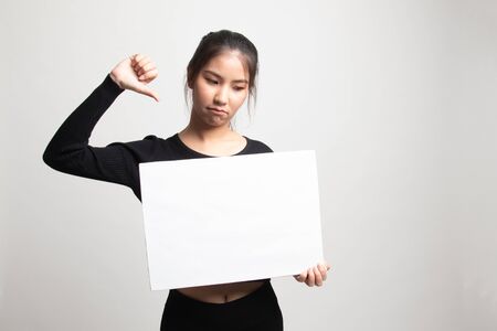 Young Asian woman show thumbs down with white blank sign on white backgroundの写真素材