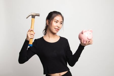 Asian woman with pig coin bank and hammer on white backgroundの写真素材