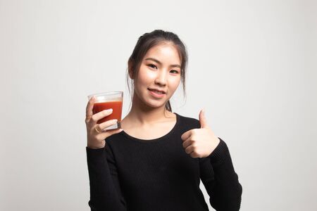 Young Asian woman thumbs up with tomato juice on white backgroundの写真素材