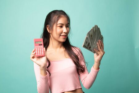 Portrait of  young asian woman  showing bunch of money banknotes on cyan backgroundの写真素材