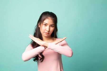 Beautiful young Asian woman say no on cyan backgroundの写真素材