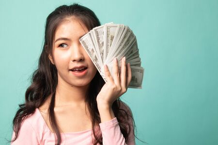 Portrait of  young asian woman  showing bunch of money banknotes on cyan backgroundの写真素材