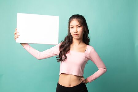 Young Asian woman with white blank sign on cyan backgroundの写真素材
