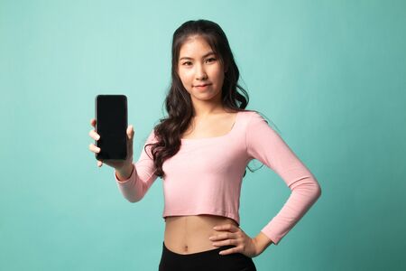 Young Asian woman with mobile phone on cyan backgroundの写真素材