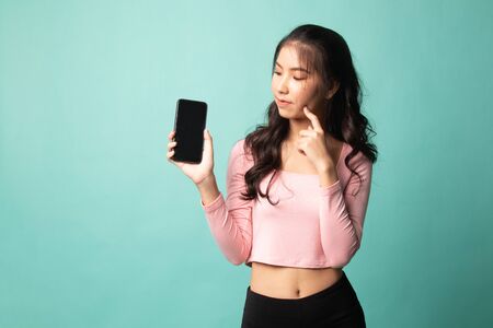 Young Asian woman with mobile phone on cyan backgroundの写真素材
