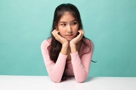 Asian girl with sad emotion on cyan backgroundの写真素材