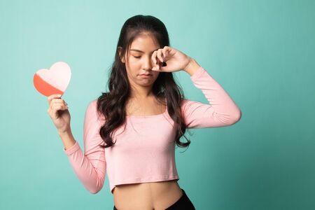 Asian woman sad and cry with red heart on cyan backgroundの写真素材
