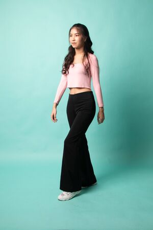 Full body of beautiful young asian woman walking on cyan backgroundの写真素材