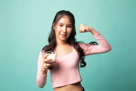 Healthy Asian woman drinking a glass of milk on cyan backgroundの写真素材