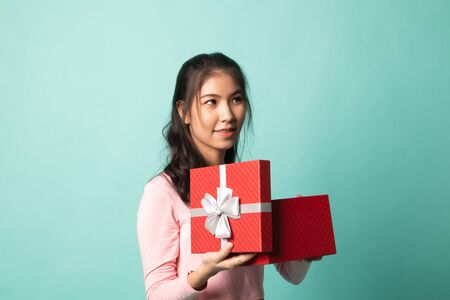 Young Asian woman open a gift box on cyan backgroundの写真素材