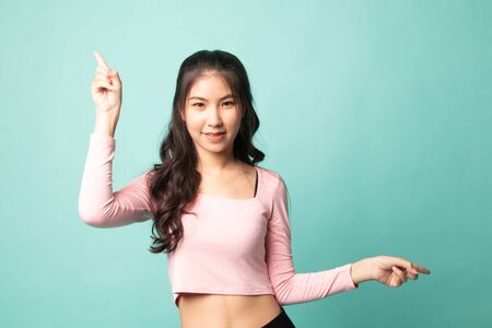 Young Asian woman point with two hands on cyan backgroundの写真素材