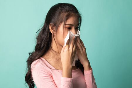 Young Asian woman got sick and flu on cyan backgroundの写真素材