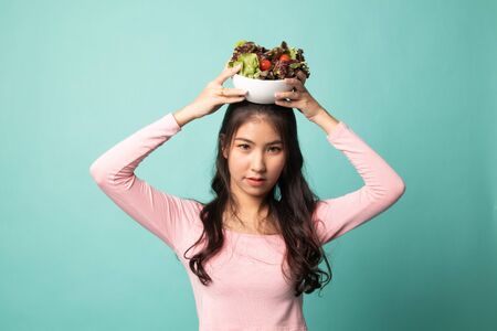 Healthy Asian woman with salad on cyan backgroundの写真素材
