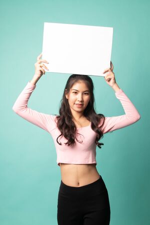Young Asian woman with white blank sign on cyan backgroundの写真素材