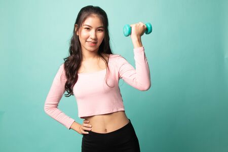 Healthy Asian woman with dumbbells on cyan backgroundの写真素材