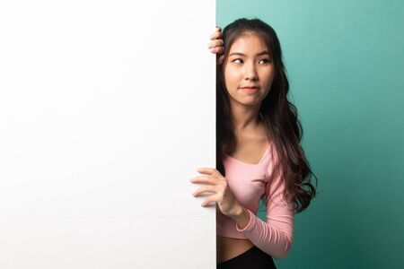 Young Asian woman with blank sign on cyan backgroundの写真素材