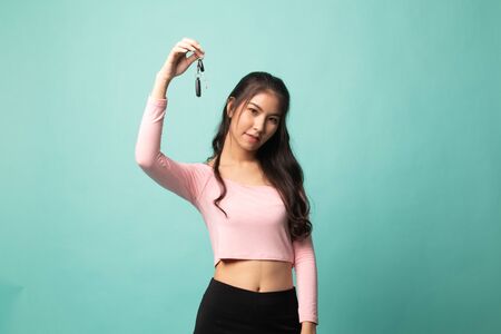 Cute asian girl showing home residence keys on cyan backgroundの写真素材