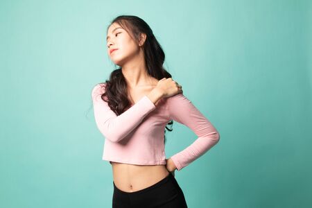 Young Asian woman got back pain on cyan backgroundの写真素材