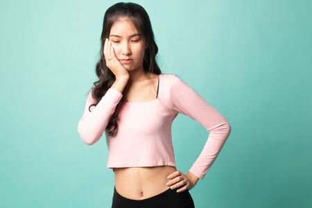 Young Asian woman got toothache on cyan backgroundの写真素材