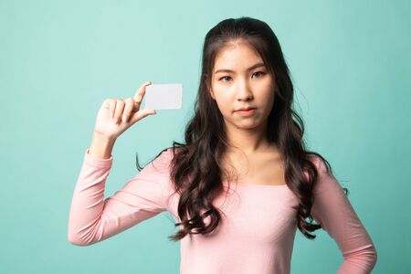 Young Asian woman with a blank card on cyan backgroundの写真素材
