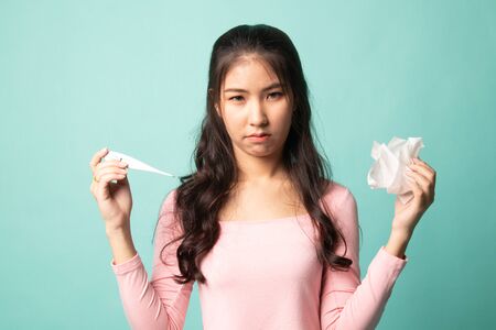 Young Asian woman got sick and flu on cyan backgroundの写真素材