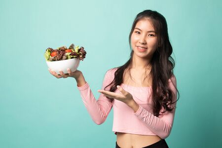 Healthy Asian woman with salad on cyan backgroundの写真素材