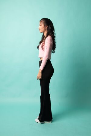 Side Full body of beautiful young asian woman on cyan backgroundの写真素材