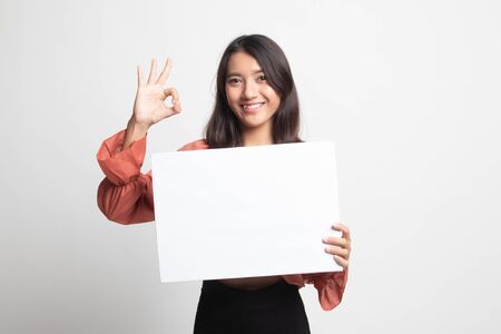 Young Asian woman show OK with white blank sign on white backgroundの写真素材