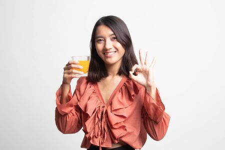 Young Asian woman drink orange juice show OK sign on white backgroundの写真素材