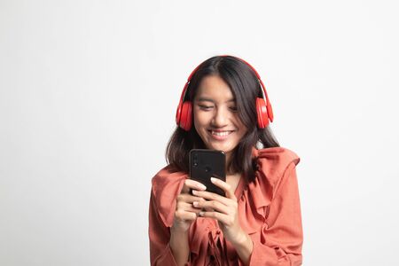 Pretty asian girl listening music with her headphones on white backgroundの写真素材