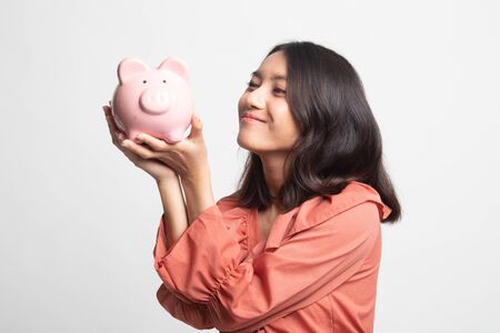 Young Asian woman kiss  a pink coin bank on white backgroundの写真素材