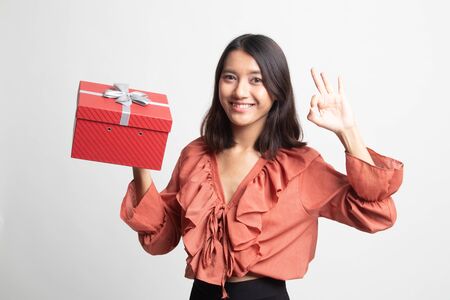 Young Asian woman show OK with a gift box on white backgroundの写真素材