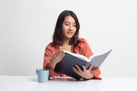 Young Asian woman read a book with cup of coffee on white backgroundの写真素材