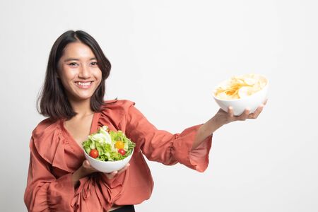 Young Asian woman with potato chips and salad on white backgroundの写真素材