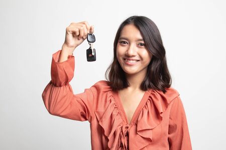 Cute asian girl showing car  key on white backgroundの写真素材