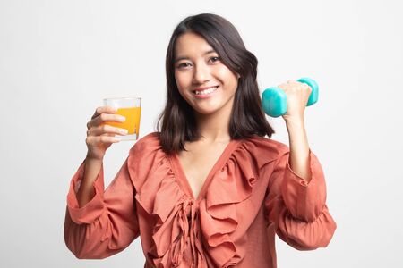 Young Asian woman with dumbbell drink orange juice on white backgroundの写真素材