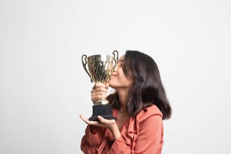 Successful young asian woman holding kissing a trophy on white backgroundの写真素材