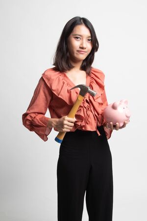 Asian woman with pig coin bank and hammer on white backgroundの写真素材