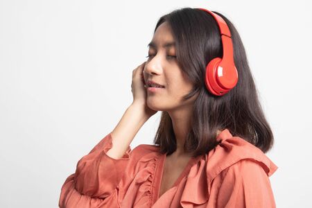 Pretty asian girl listening music with her headphones on white backgroundの写真素材
