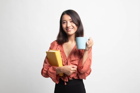 Young Asian woman with a book and cup of coffee on white backgroundの写真素材