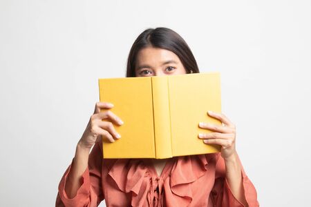 Young Asian woman with a book cover her face on white backgroundの写真素材