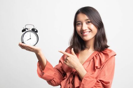 Young Asian woman point to a clock on white backgroundの写真素材
