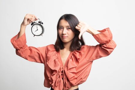 Young Asian woman thumbs down with a clock on white backgroundの写真素材