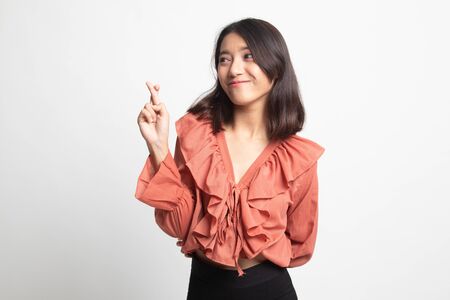 Beautiful young Asian woman cross finger on white backgroundの写真素材
