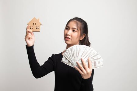 Happy young asian woman with house model and bunch of money banknotes on white backgroundの写真素材