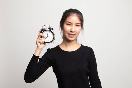 Young Asian woman with a clock on white backgroundの写真素材