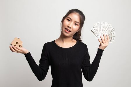 Happy young asian woman with house model and bunch of money banknotes on white backgroundの写真素材