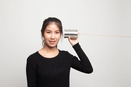 Young Asian woman with tin can phone on white backgroundの写真素材